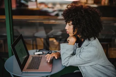 Young woman focused on her laptop while working at a cozy coffee shop.