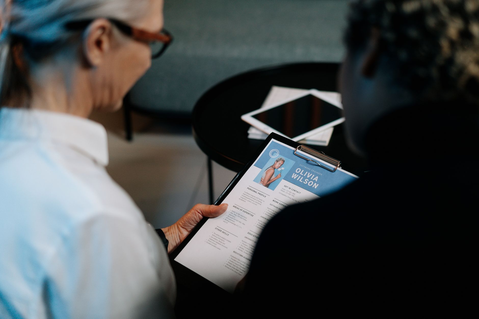 Business professionals conducting an interview with resume on clipboard in an office setting.